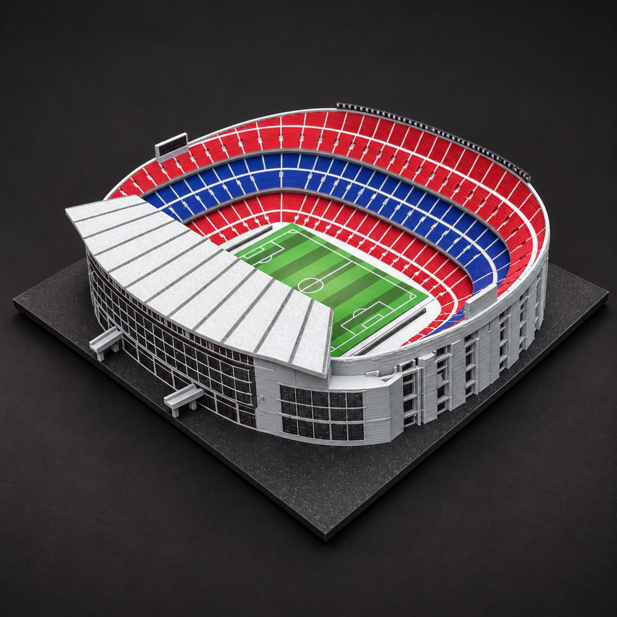 Model Camp Nou ze strany hlavní tribuny, s bílou střechou a členěnou šedou fasádou.